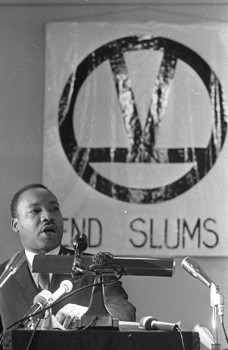 Martin Luther King Jr. with a sign that says "End Slums"