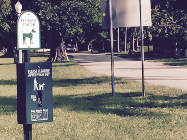 a sign posted, along with a plastic bag dispenser, for owners of dogs to pick up after their dogs 