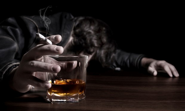 man with head on bar with cigarette and whiskey glass