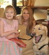 a little girl and an adult woman smiling next to a yawning dog