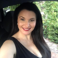justine sitting in her car smiling wearing a black dress