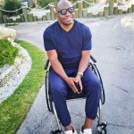 Dwight outside in his wheelchair smiling and wearing sunglasses