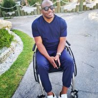 Dwight outside in his wheelchair smiling and wearing sunglasses Dwight outside in his wheelchair smiling and wearing sunglasses