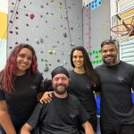 Jordan and three friends in front of a rock climbing wall