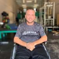 Alfredo looking at the camera sitting in his wheelchair smiling