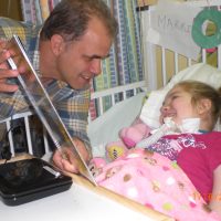 Matt reading a book to a medically fragile child in a bed Matt reading a book to a medically fragile child in a bed