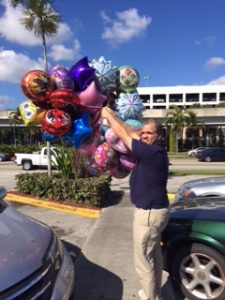 Matt holding a bunch of balloons outside.