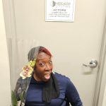 a woman sitting and holding a flower with a big smile on her face.