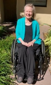 a woman wearing a green sweater sitting in a wheelchair outside