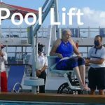 a pool lift on a cruise ship with people helping a woman into the pool