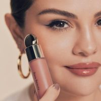 selena gomez holding a bottle of rare beauty make up next to her face selena gomez holding a bottle of rare beauty make up next to her face